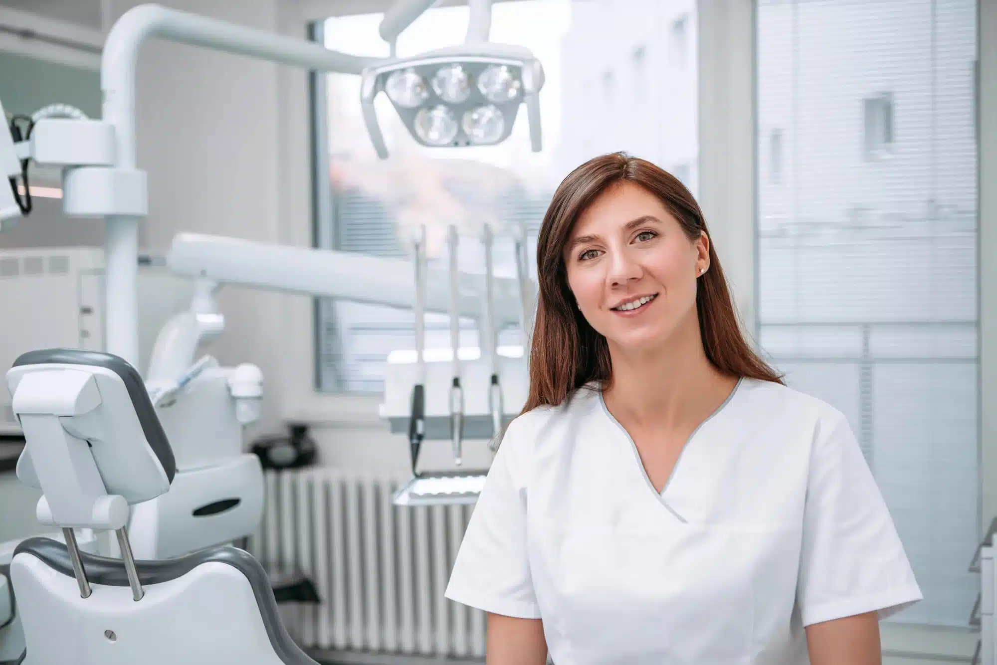 A female dentist in Downriver Detroit wearing white scrubs in dental office