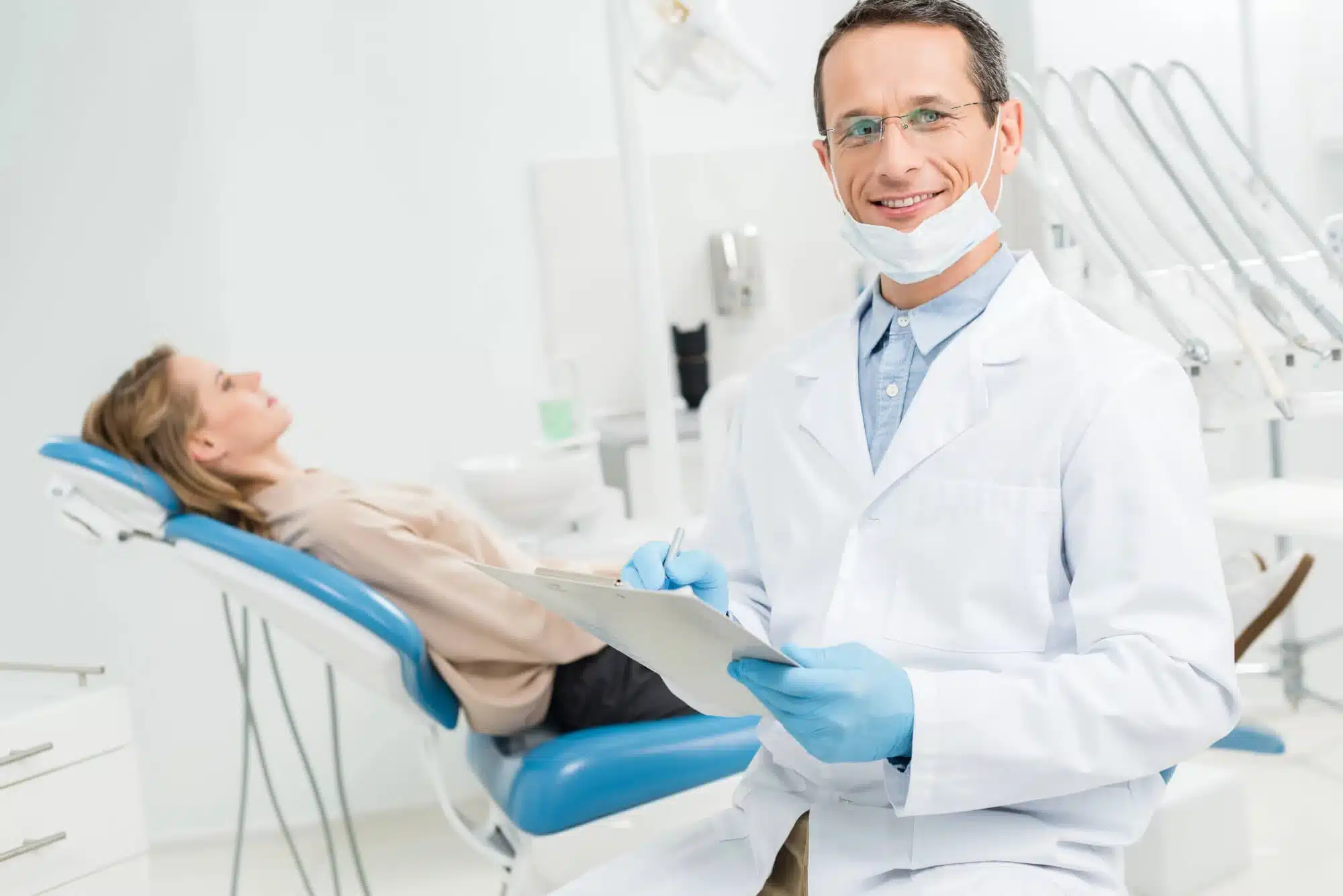 Doctor completing patient health checklist before tooth extractions in Riverview, MI